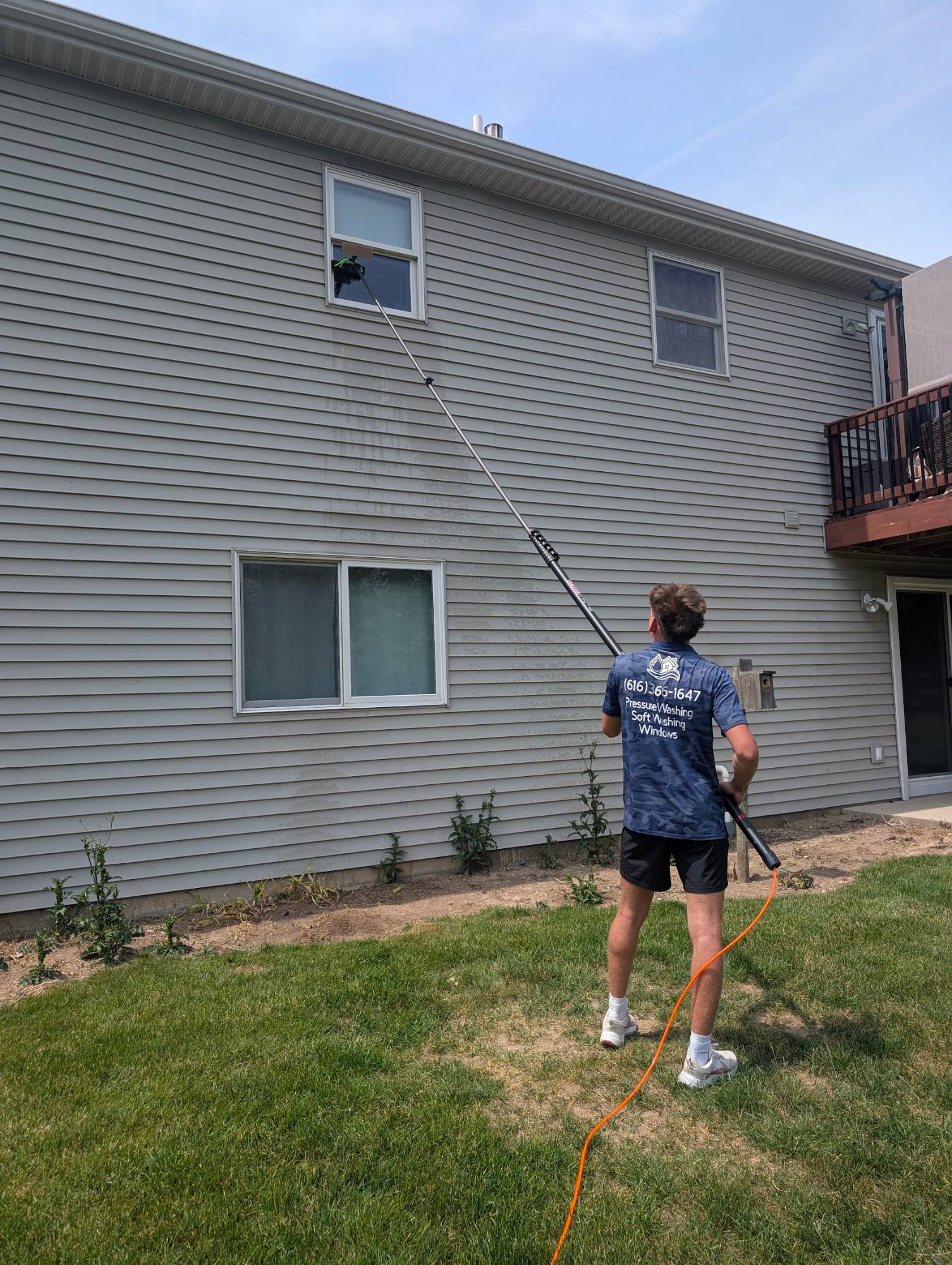 Technician cleaning second-story windows with a water-fed pole
