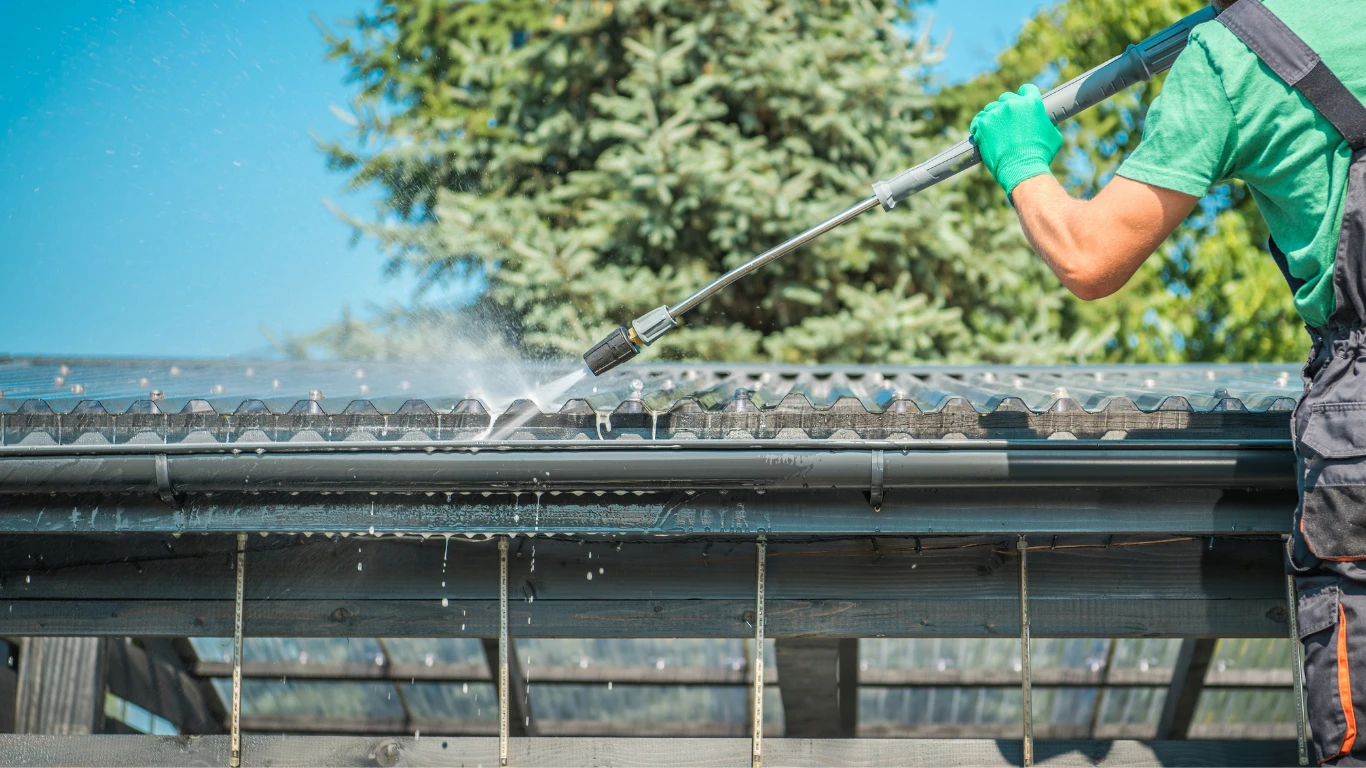 Technician rinsing a commercial roofline and gutter with low pressure
